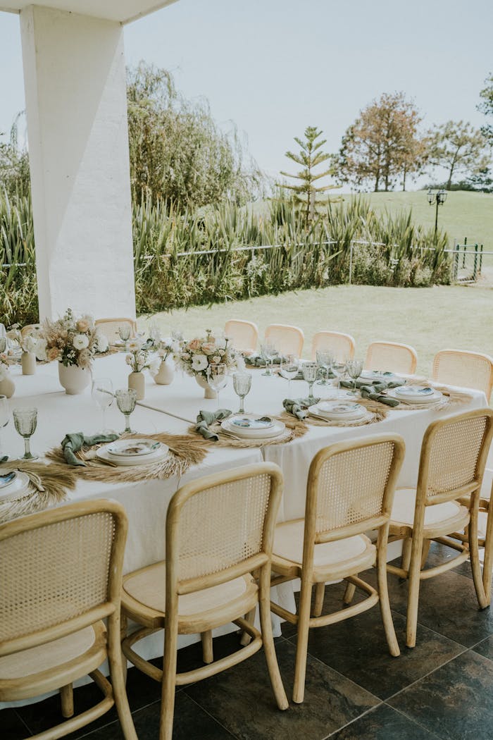 Chic outdoor table setting for a celebration with white decor and natural elements.